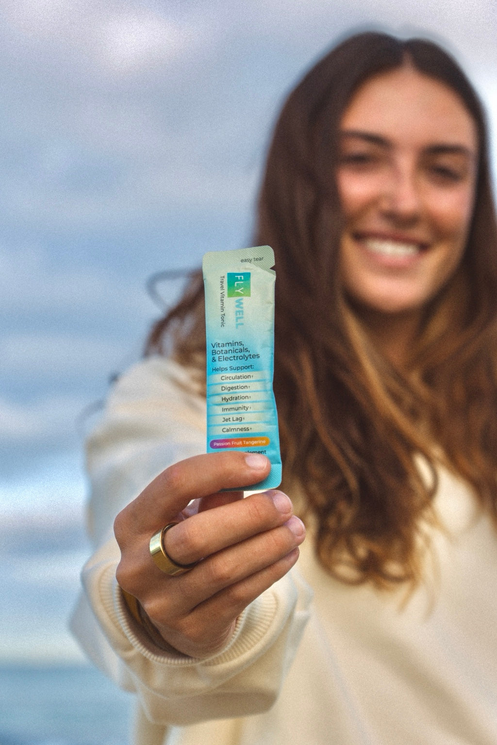 Woman holding a FlyWell Passion Fruit Tangerine travel vitamin stick