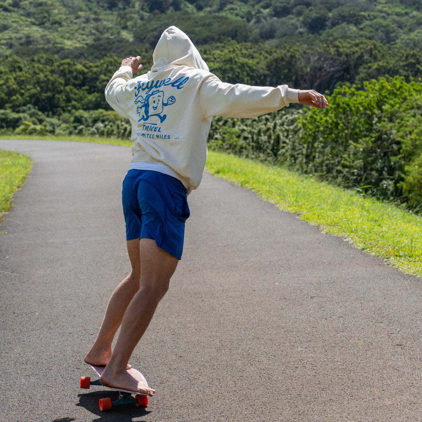 Person skateboarding on a road with greenery in the background